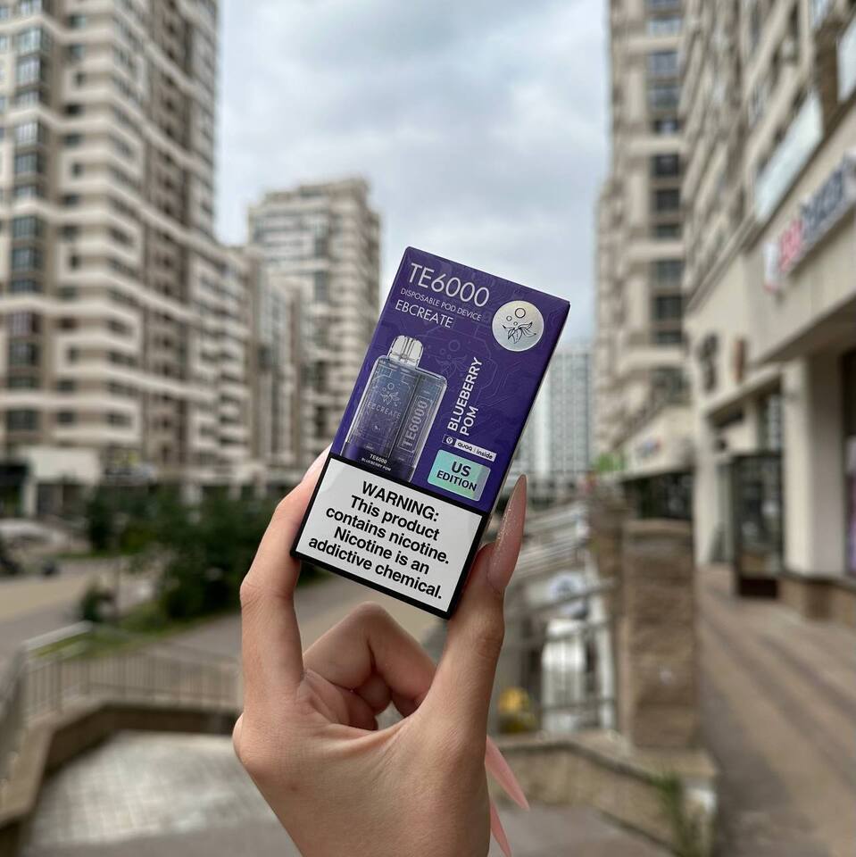 Hand holding a vape device packaging with cityscape in the background